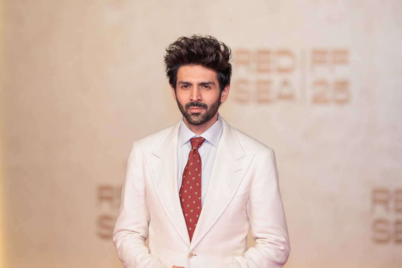 Actor Kartik Aaryan wearing a white suit at the 2025 Red Sea International Film Festival