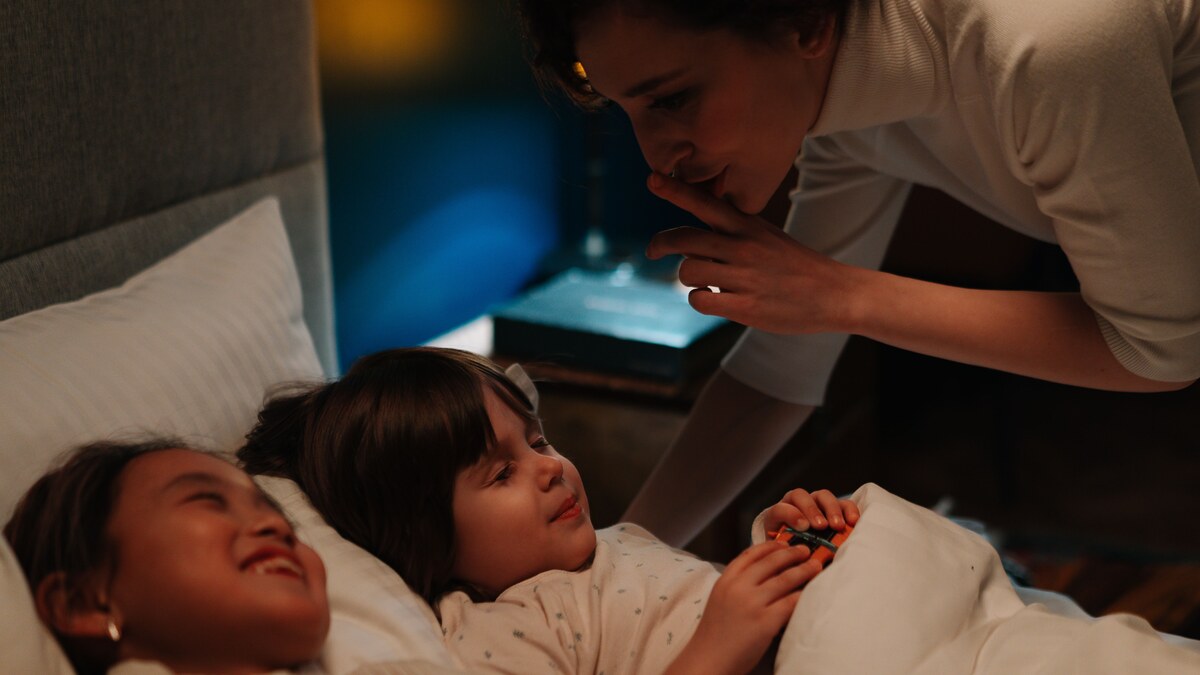 A caregiver comforting two children at bedtime in a representative stock photograph