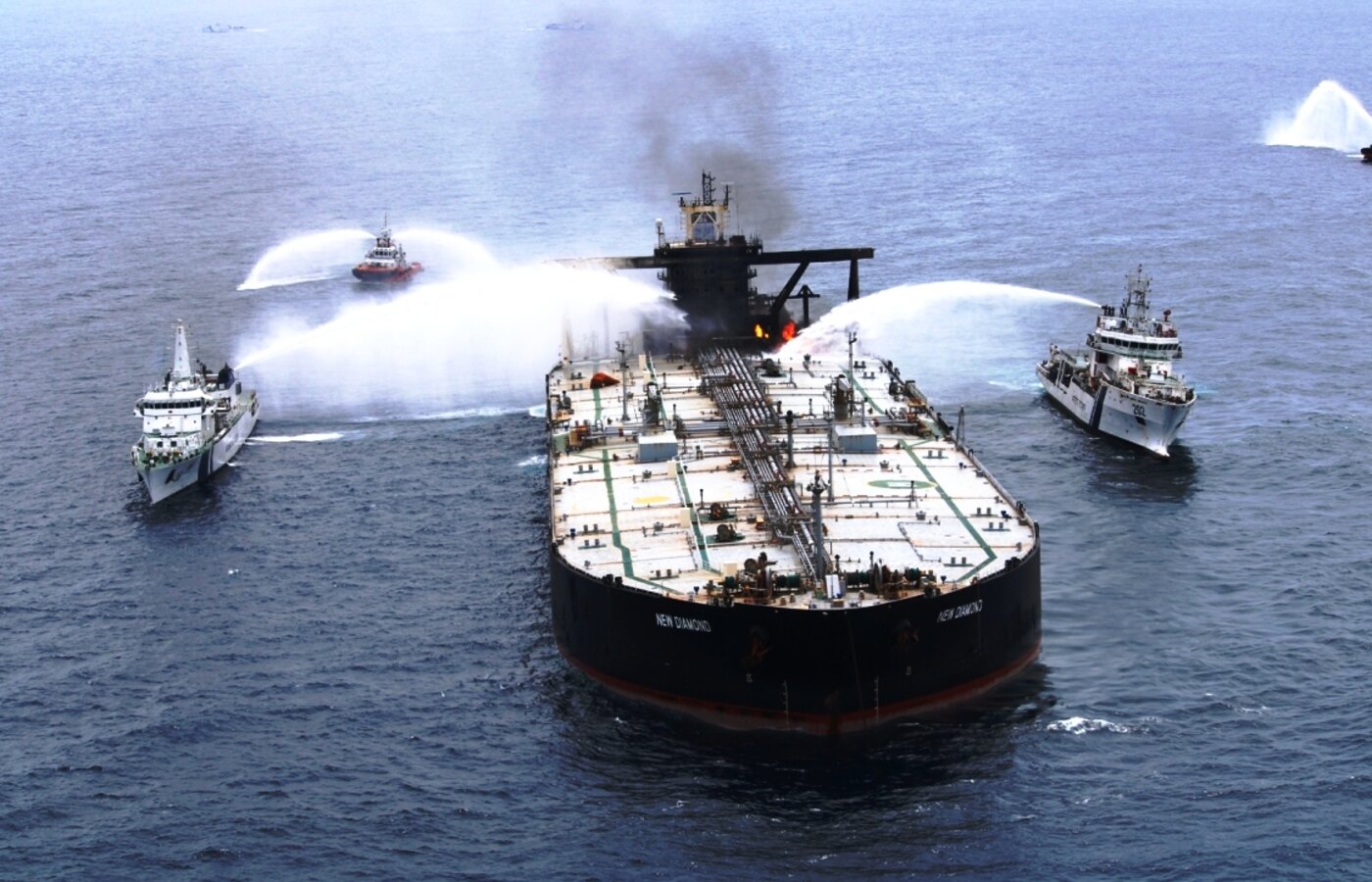 Indian Coast Guard ships spraying water during a firefighting operation at sea