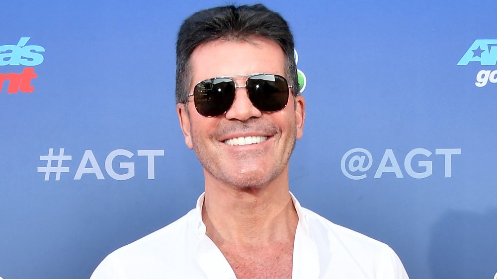 Simon Cowell posing in front of an America's Got Talent backdrop