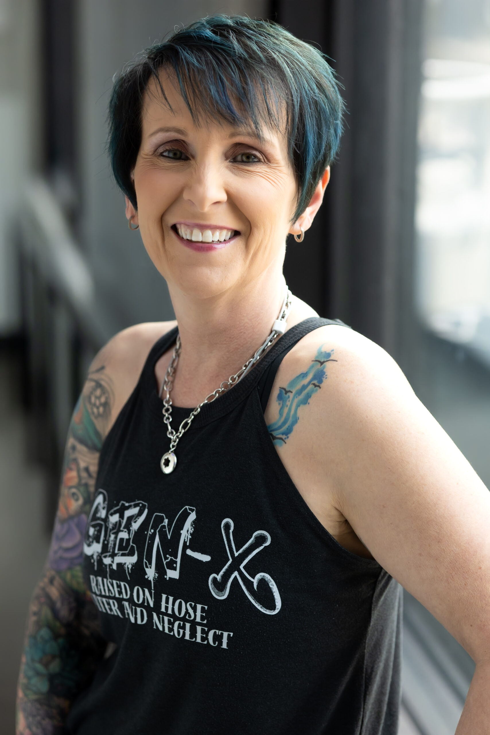 The Real Slim Sherri smiling in an official portrait, wearing a black Gen X tank top
