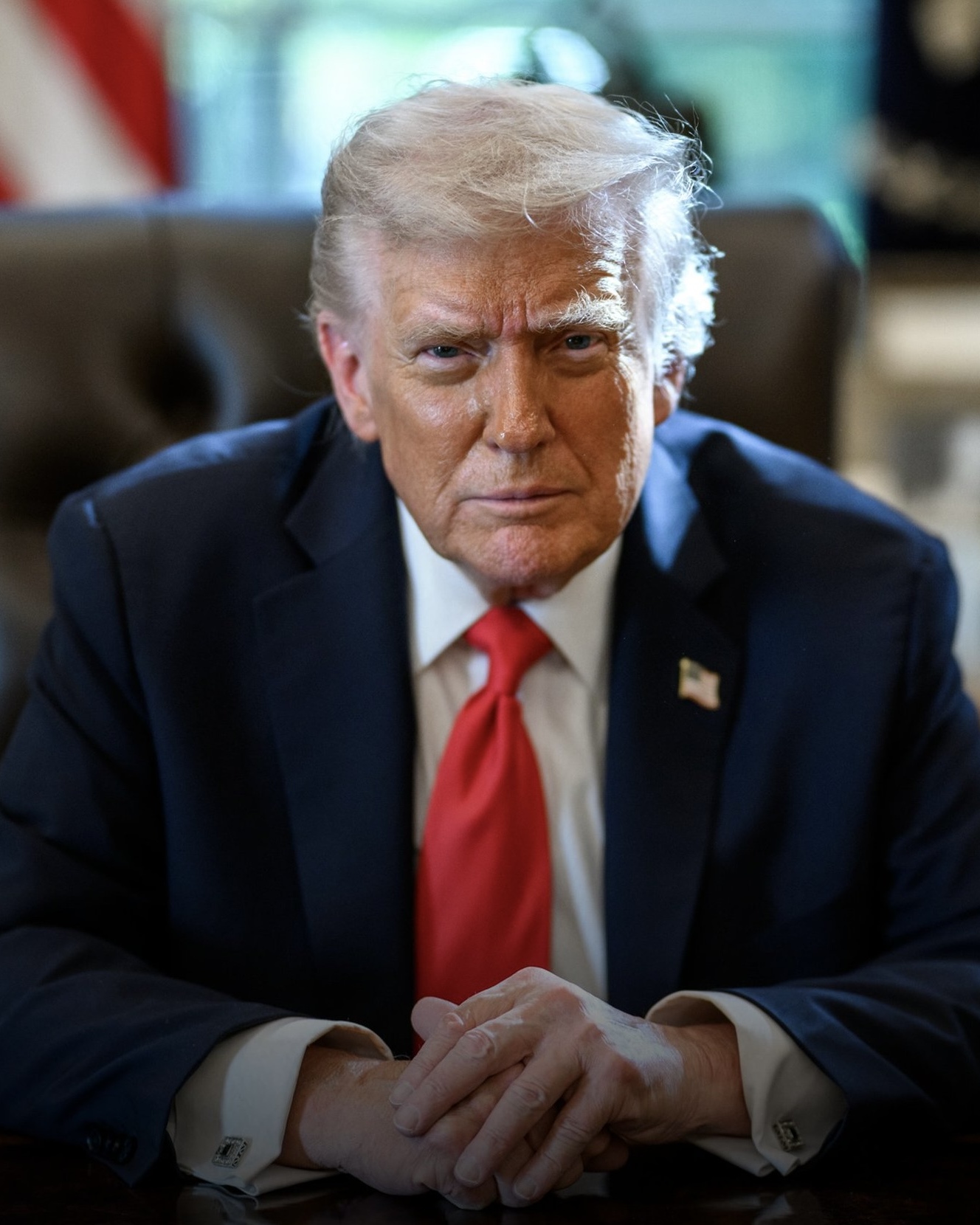 President Donald Trump seated at the Resolute Desk in the Oval Office