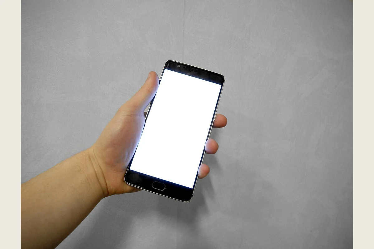 A hand holding a smartphone with a blank screen