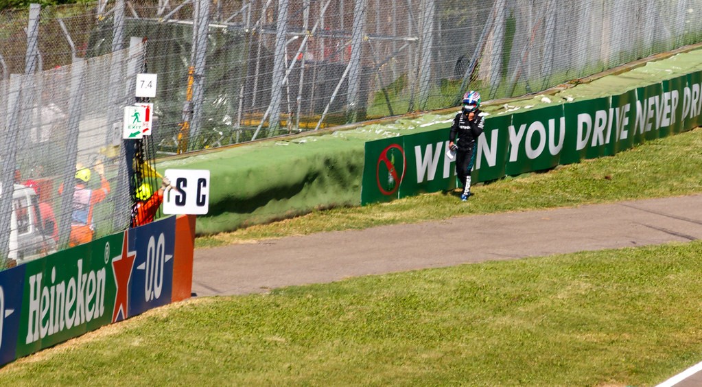 Kimi Antonelli in his racing suit and helmet beside the circuit barriers at Imola in May 2025