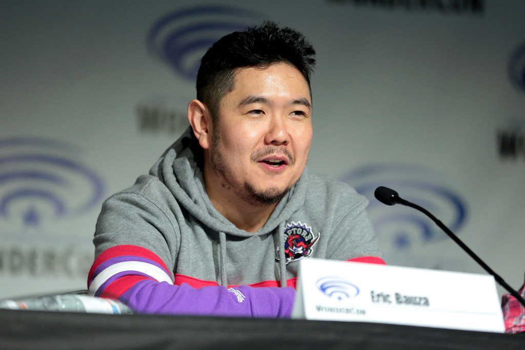 Eric Bauza speaking into a microphone during a panel at WonderCon in 2018.