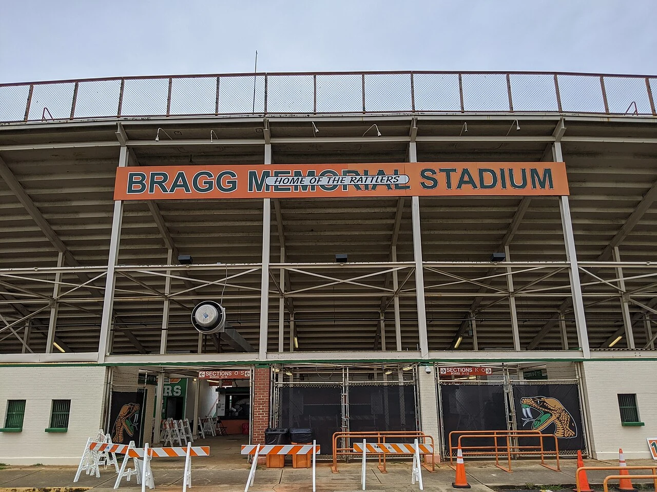 The eastern entrance of Bragg Memorial Stadium, with an orange stadium sign above gates and construction barriers