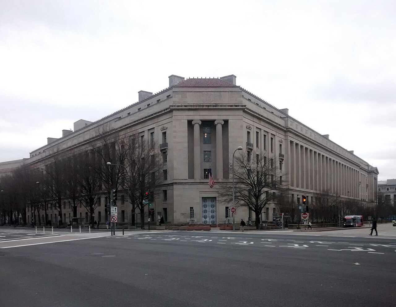 The Robert F. Kennedy Department of Justice Building seen from a Washington street corner, with columns, an American flag and traffic signals