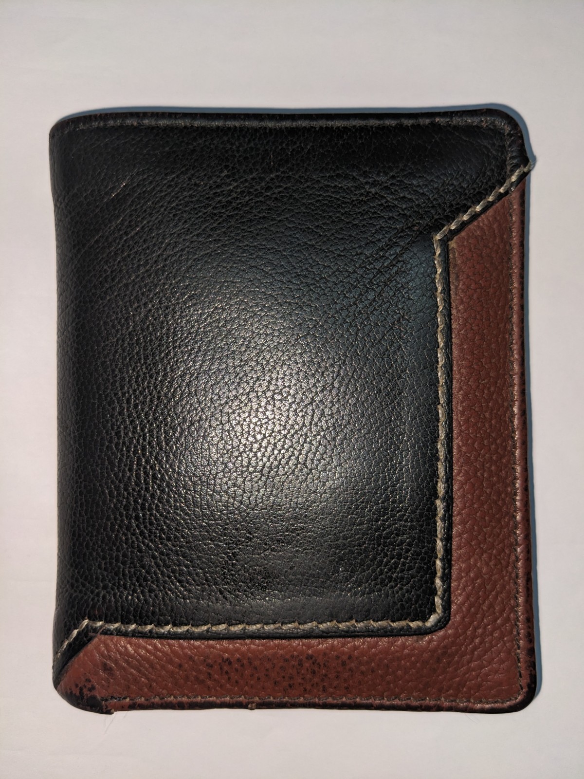 Close-up photograph of a worn black and brown leather wallet