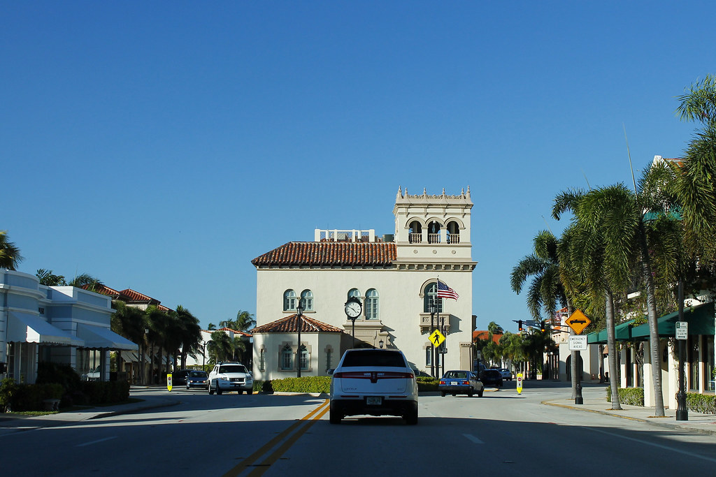 Palm Beach Town Hall’s pale Mediterranean-style facade and tower, seen from the street with palm trees