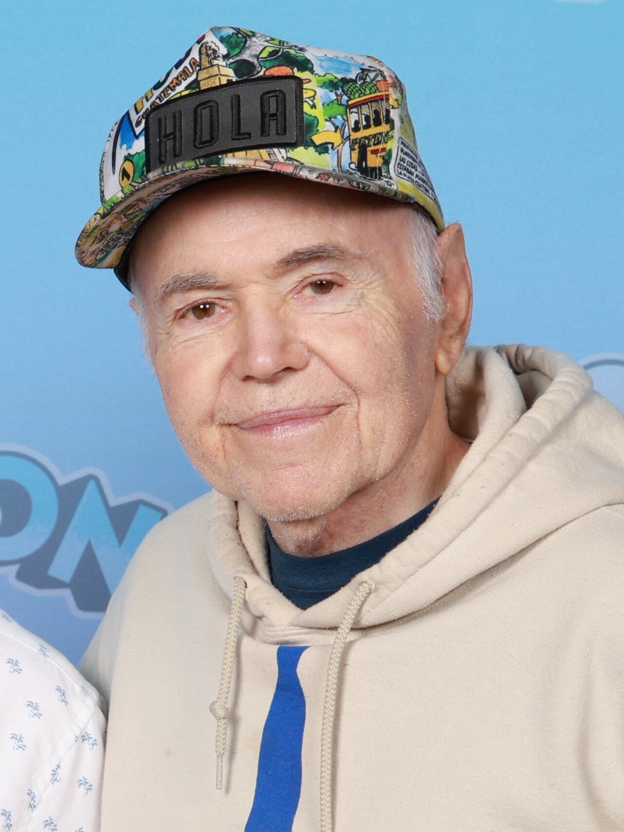 Walter Koenig wearing a patterned baseball cap and a light hoodie in front of a blue GalaxyCon backdrop