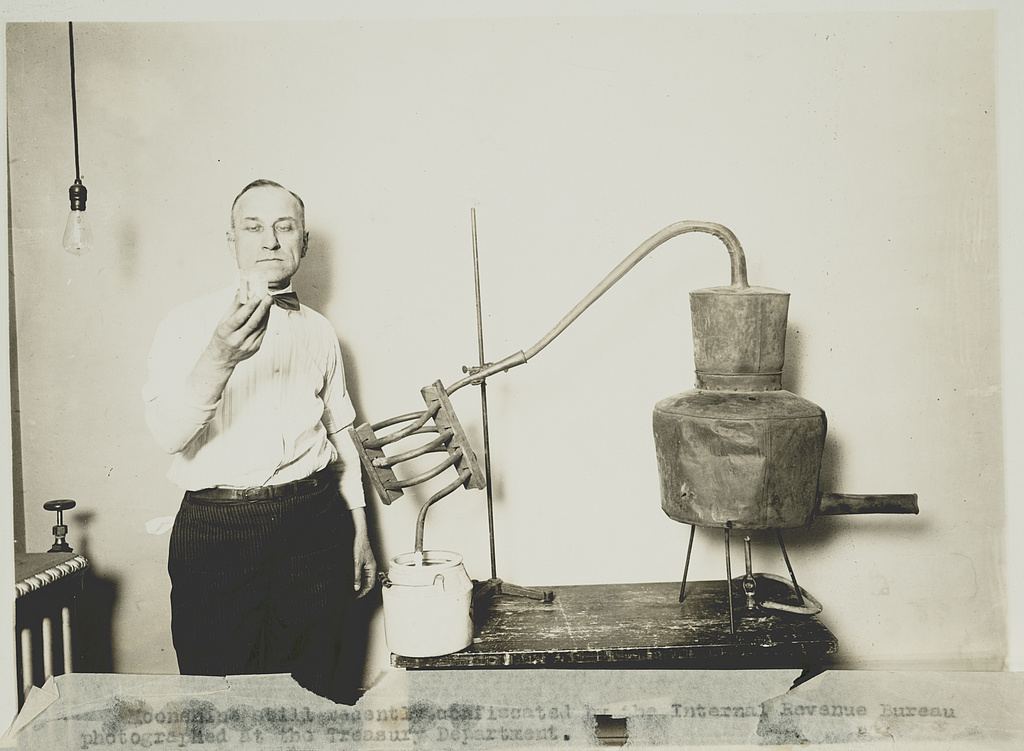 Historical file photograph of an unidentified man beside a confiscated still at the Treasury Department, between 1921 and 1932; unrelated to the Wilkes County case.
